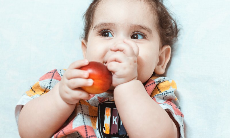 Barn sidder ned og spiser et æble Barn sidder ned og spiser et æble